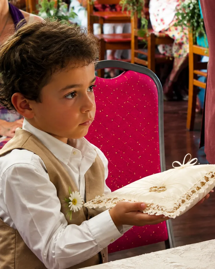 Un adorable enfant porte les alliances des mariés sur un élégant coussin lors de la cérémonie. Une photo pleine de tendresse qui capture l’innocence, l’émotion et la magie de ce moment symbolique du mariage de Manon et Adrien. 💍🤍